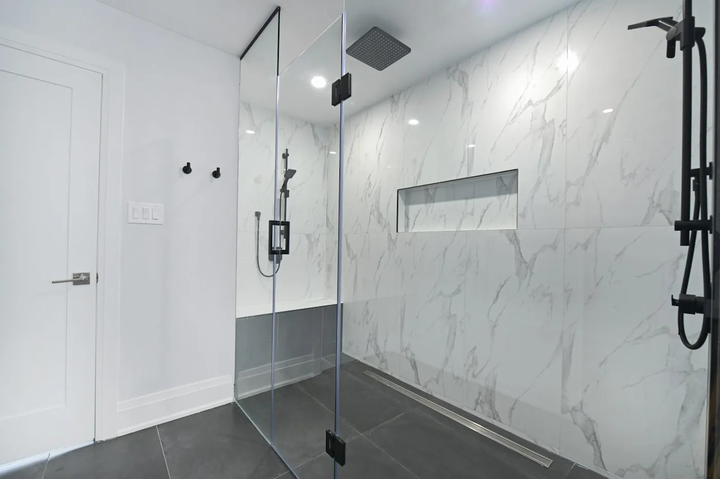 Walk-in shower with marble walls and glass enclosure