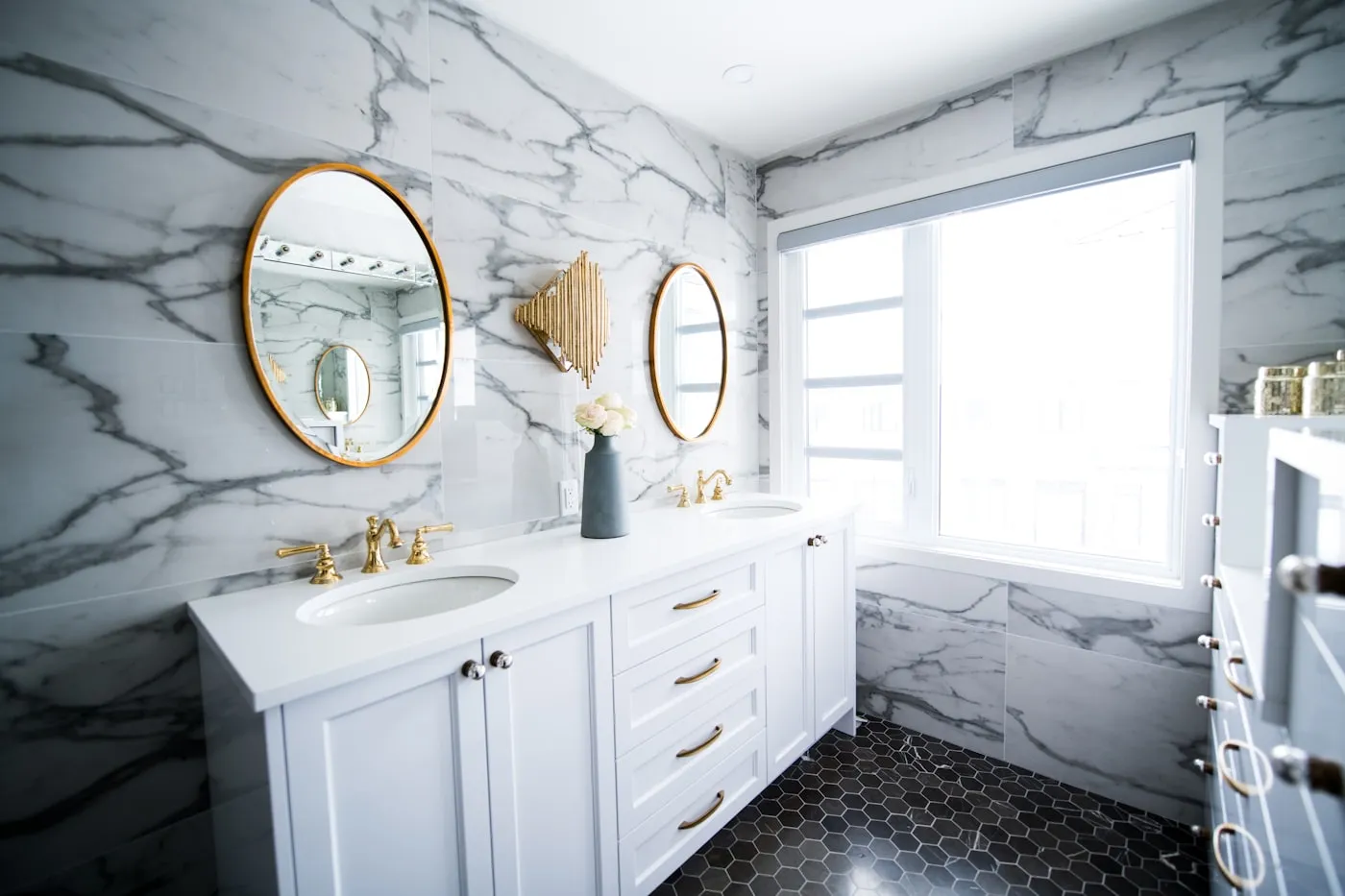 Marble bathroom with white vanity and round mirrors